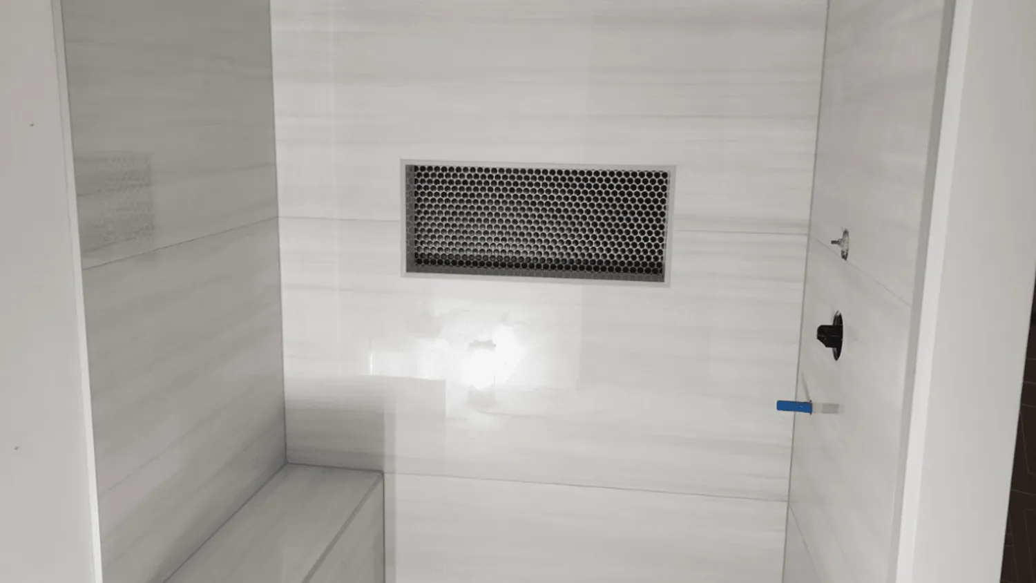 rectangular shower niche with hexagonal tile background installed in marble-tiled shower wall